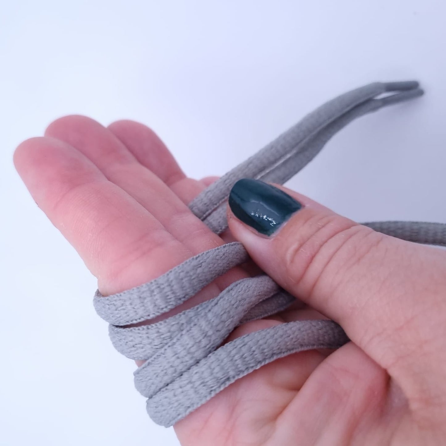 Hand hält graue halbrunde Schnürsenkel