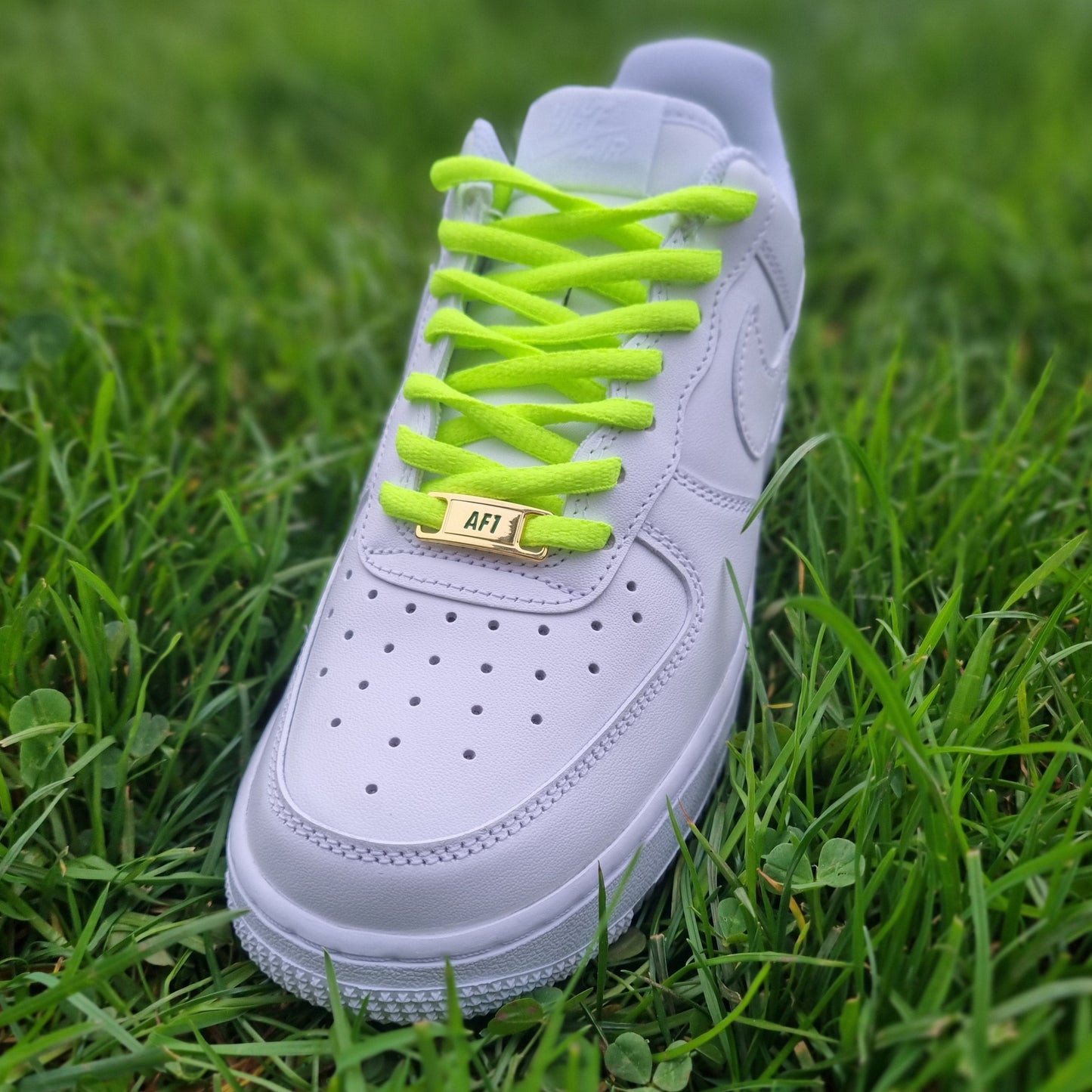 Halbrunde neon-grüne Schnürsenkel als auffälliges Detail in weißen AF1 Sneakern