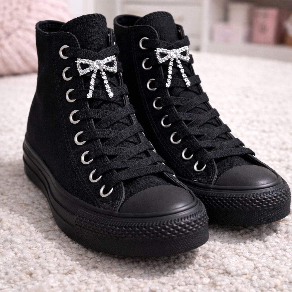 Silver rhinestone bows attached to black high Converse boots.