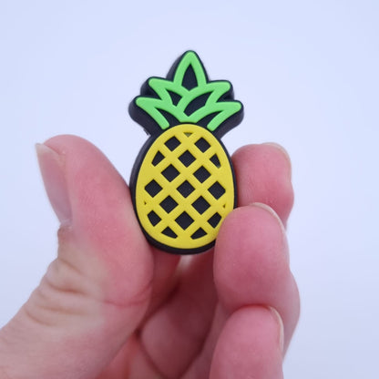 Hand hält Crocs Schmuck Ananas